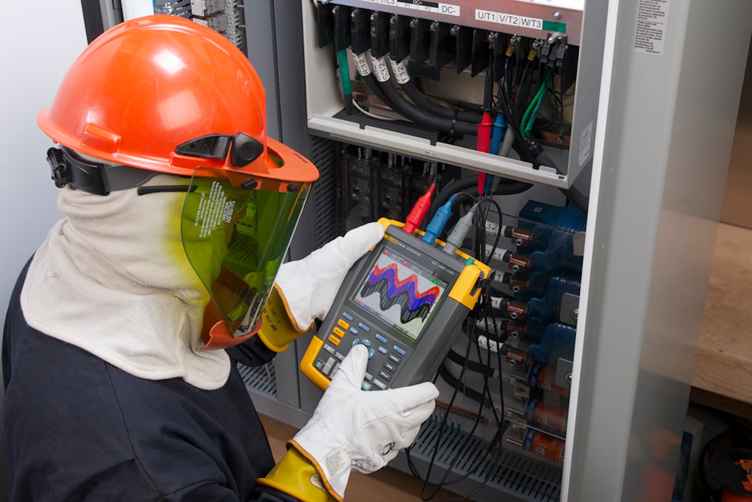 A technician in a work environment using a Fluke portable handheld oscilloscope multimeter